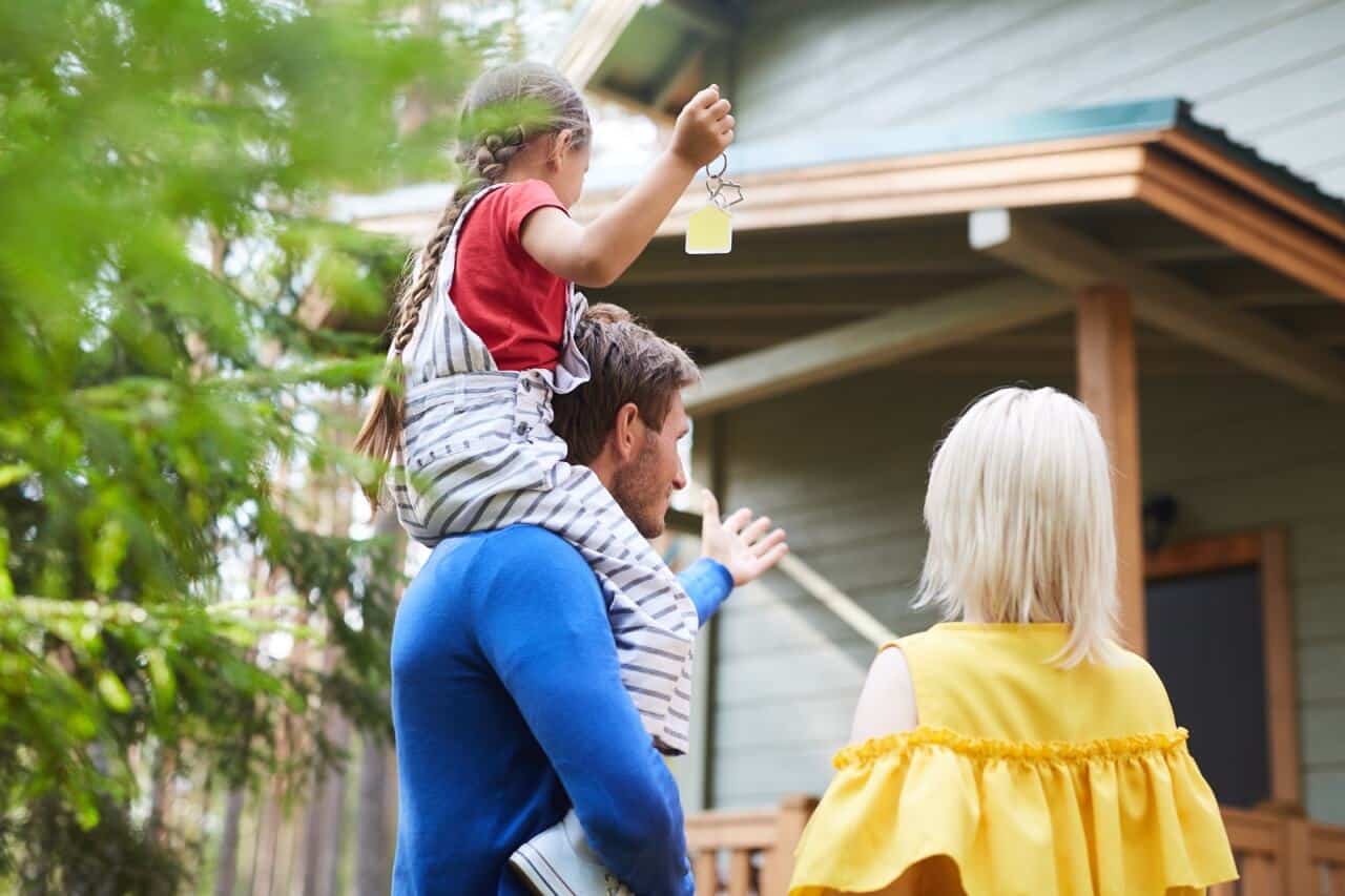 Young family of three standing by their new house in the country and going to come in
